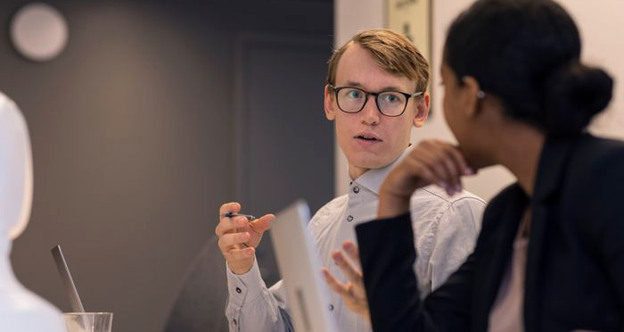 Två personer sitter vid ett bord och pratar med varandra.