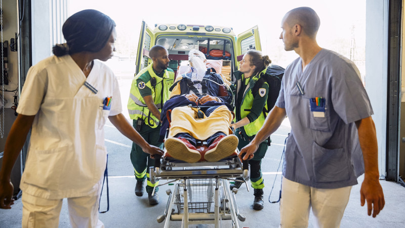  Vårdpersonal transporterar patient mellan ambulans och sjukhus.