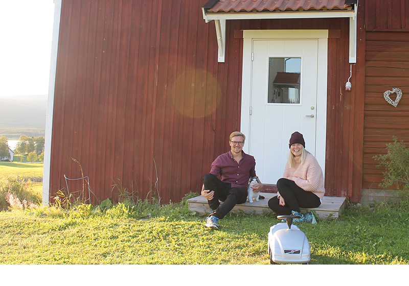 en man och en kvinna sitter på farstubron till ett rött hus