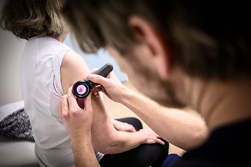 Läkare som undersöker hudförändring med ett dermatoskop