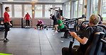 Personer som tränar i ett gym tillsammans med en ledare.